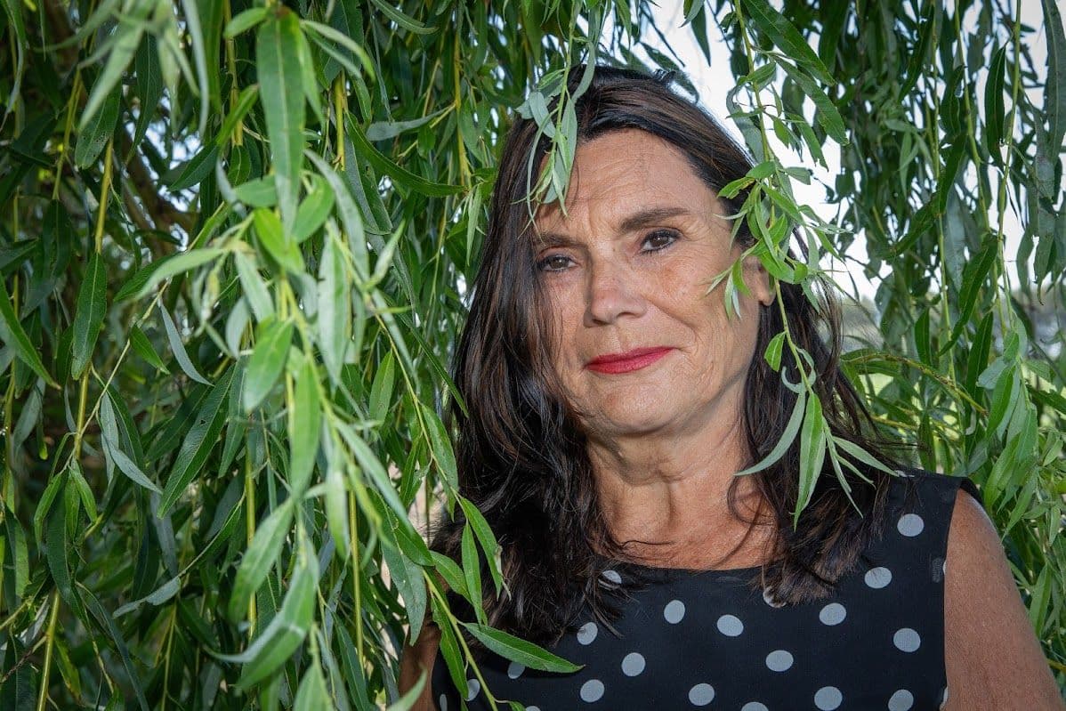 Judy Hooymeyer tussen de takken van een treurwilg